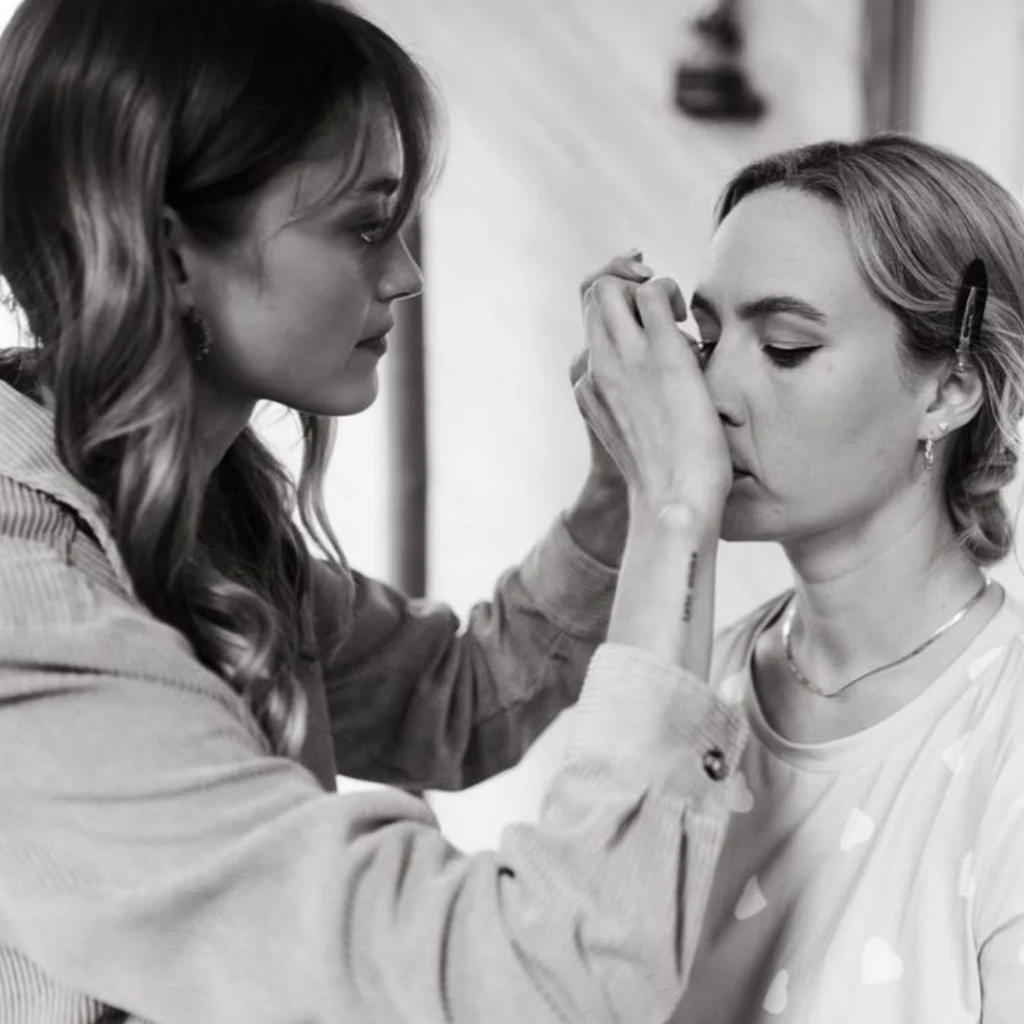A person carefully applies makeup to another person's face