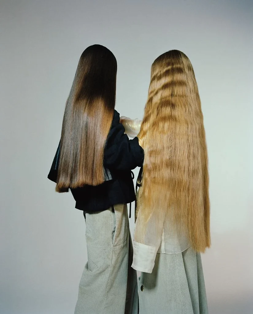 Two figures with long, flowing hair stand side by side, showcasing different textures