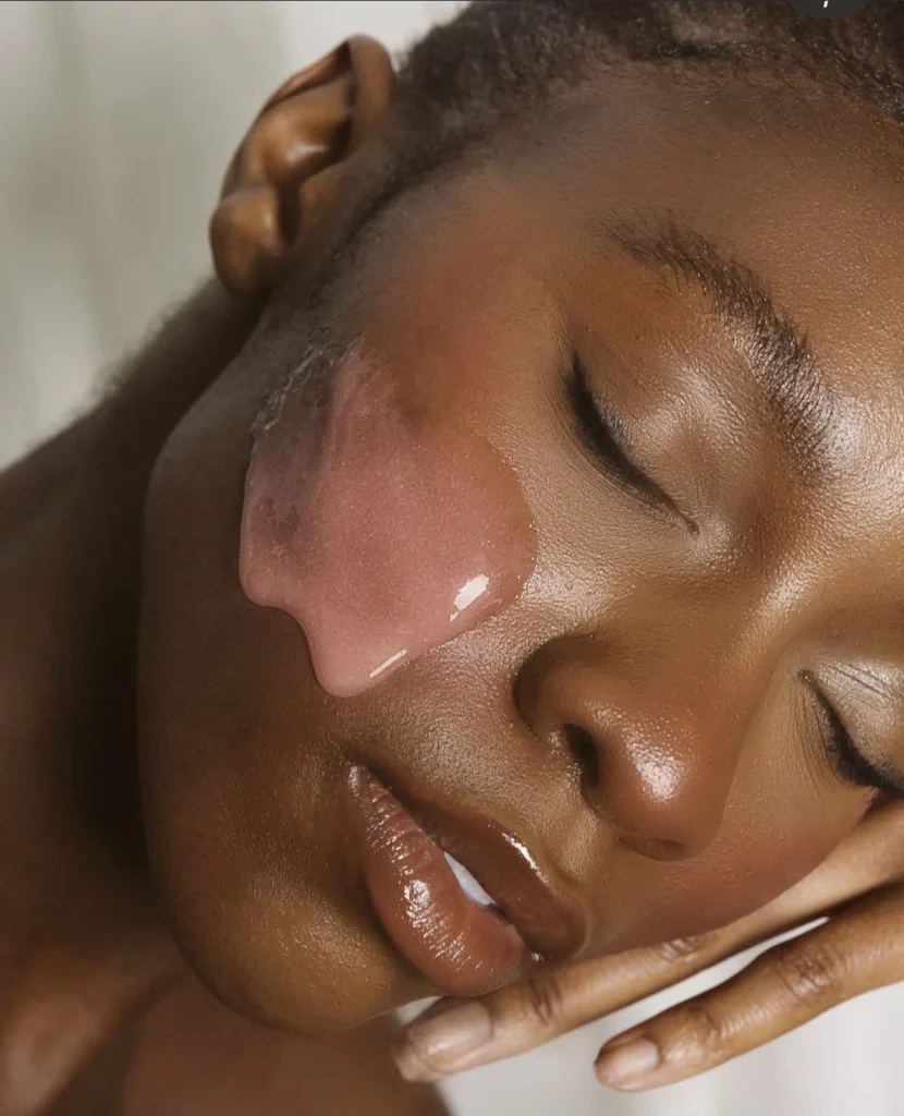 A person with closed eyes rests their face, adorned with a pink gel