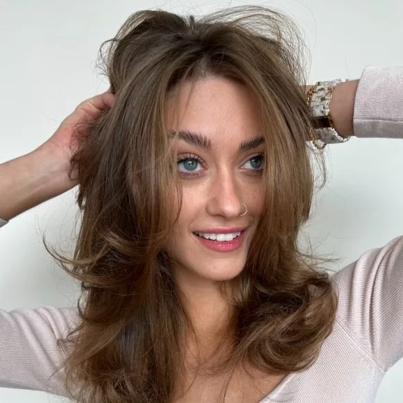 A woman smiles while playfully arranging her hair