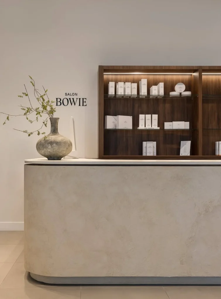 A minimalist reception desk displays elegant skincare products in a serene environment