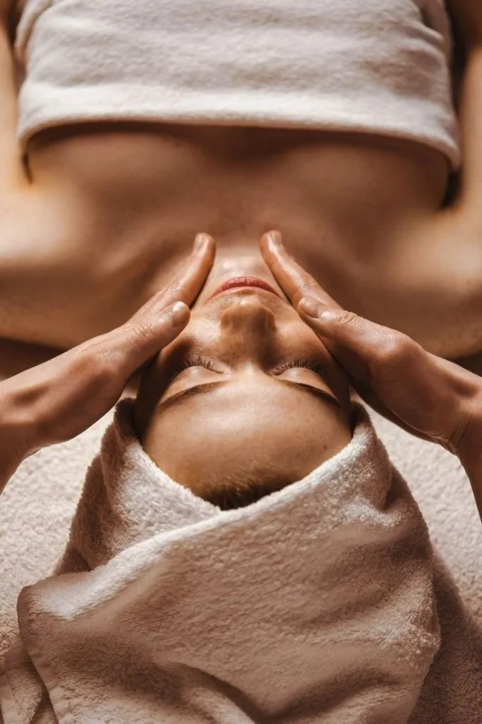 A person receives a relaxing facial massage with a towel wrapped around their head