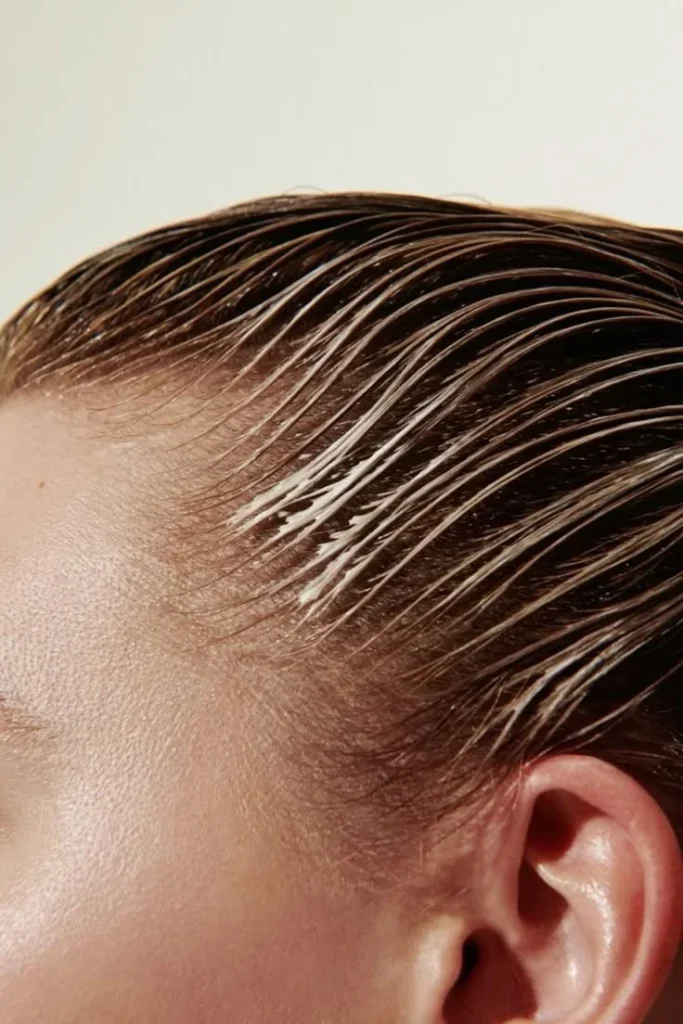 Close-up of slicked-back hair showcasing shiny, textured strands against a light background