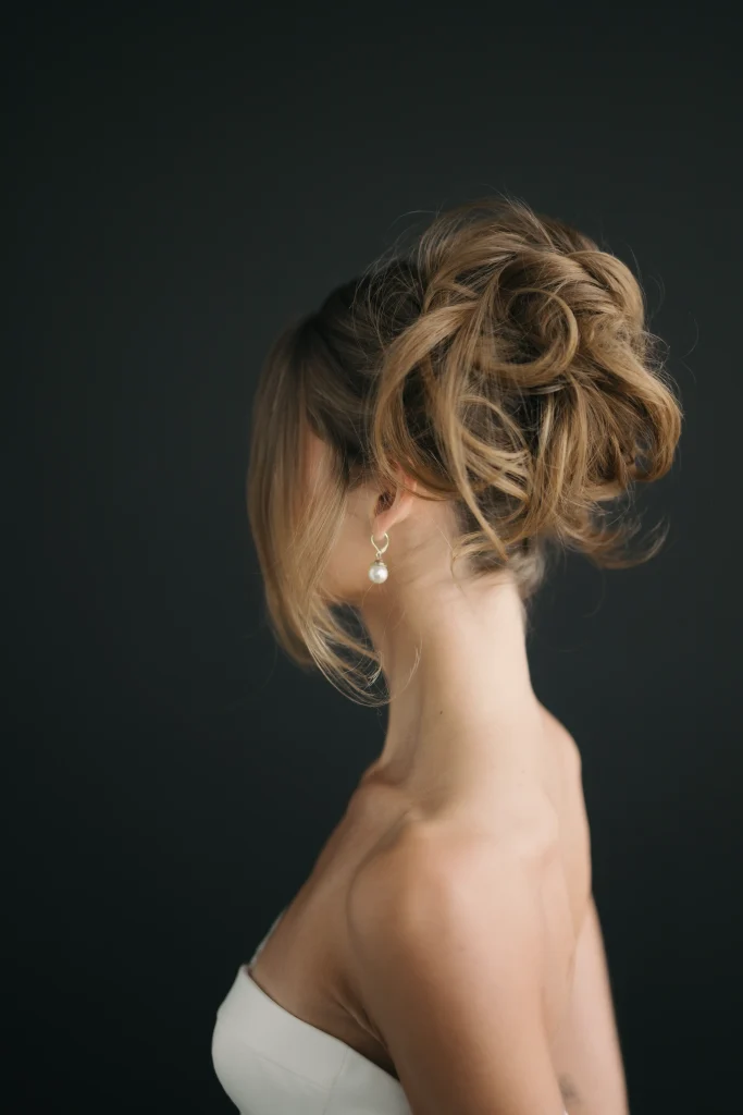 A woman with elegantly styled hair gazes sideways against a dark background