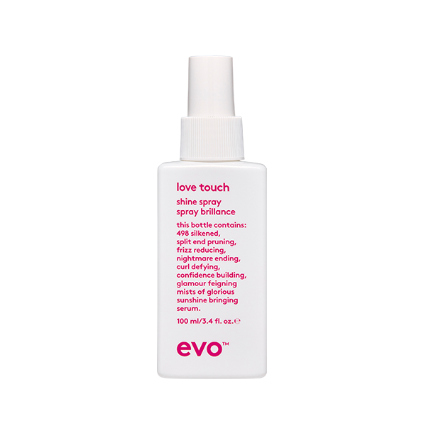 A clear spray bottle stands upright, highlighting its sleek design and colorful label