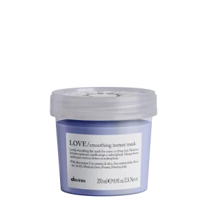 A small, light purple jar of smoothing hair mask with a clear lid sits against a white background