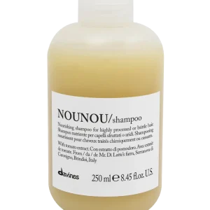 A clear bottle of shampoo with a minimalist label displays cream-colored liquid inside