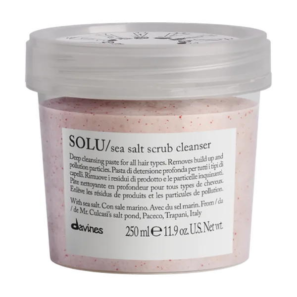 A clear container holds a pink, textured sea salt scrub with an attached label