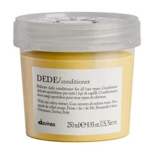 A small, transparent container holds yellow conditioner with elegant labeling and a minimalist design