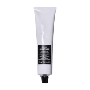 A white tube of hand balm with a black label lies against a plain background