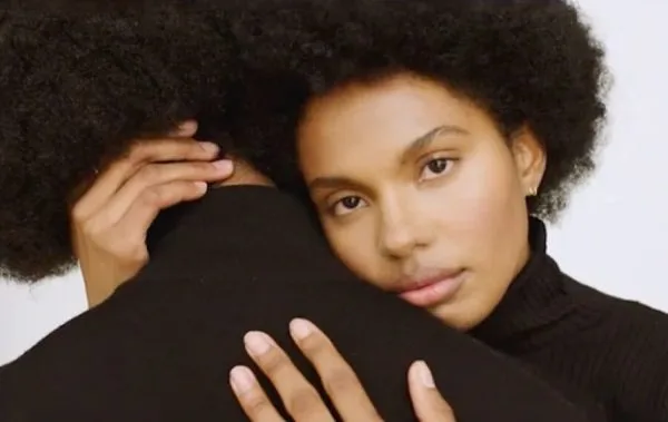 A person gently embraces another, creating an intimate and tender moment