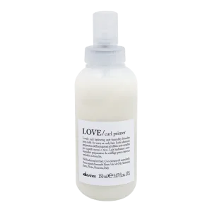 A clear spray bottle contains a creamy hair product labeled as curl primer