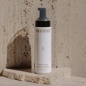 A sleek bottle with a pump is displayed against a textured stone background