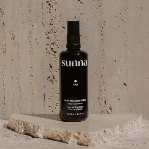 A sleek black spray bottle rests on a textured stone surface