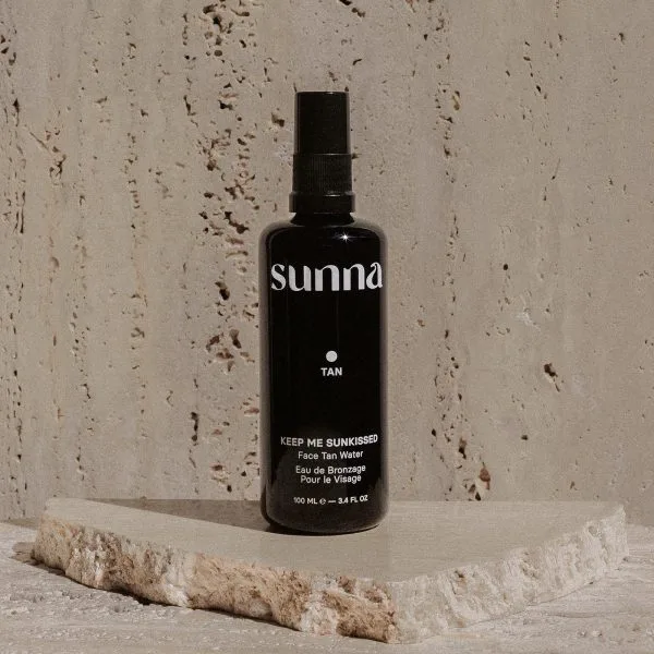 A sleek black spray bottle rests on a textured stone surface