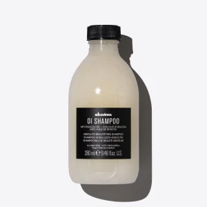 A light-colored bottle of shampoo with a black cap sits against a plain background