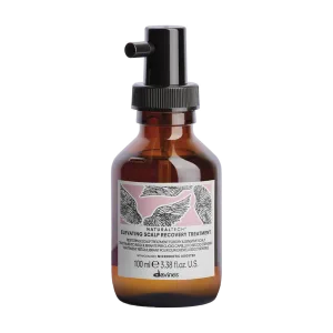 A brown glass bottle with a spray top contains a scalp treatment solution