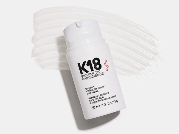 A sleek white bottle with a pump sits on a creamy, textured surface