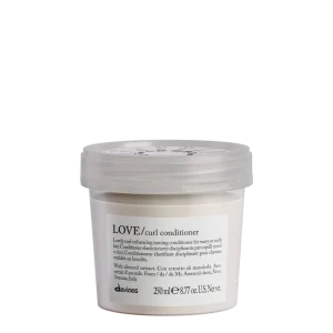 A white, branded container of curl conditioner sits against a plain background