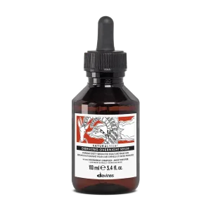 A dark glass bottle with a dropper cap contains a lightweight serum with floral and graphic labeling